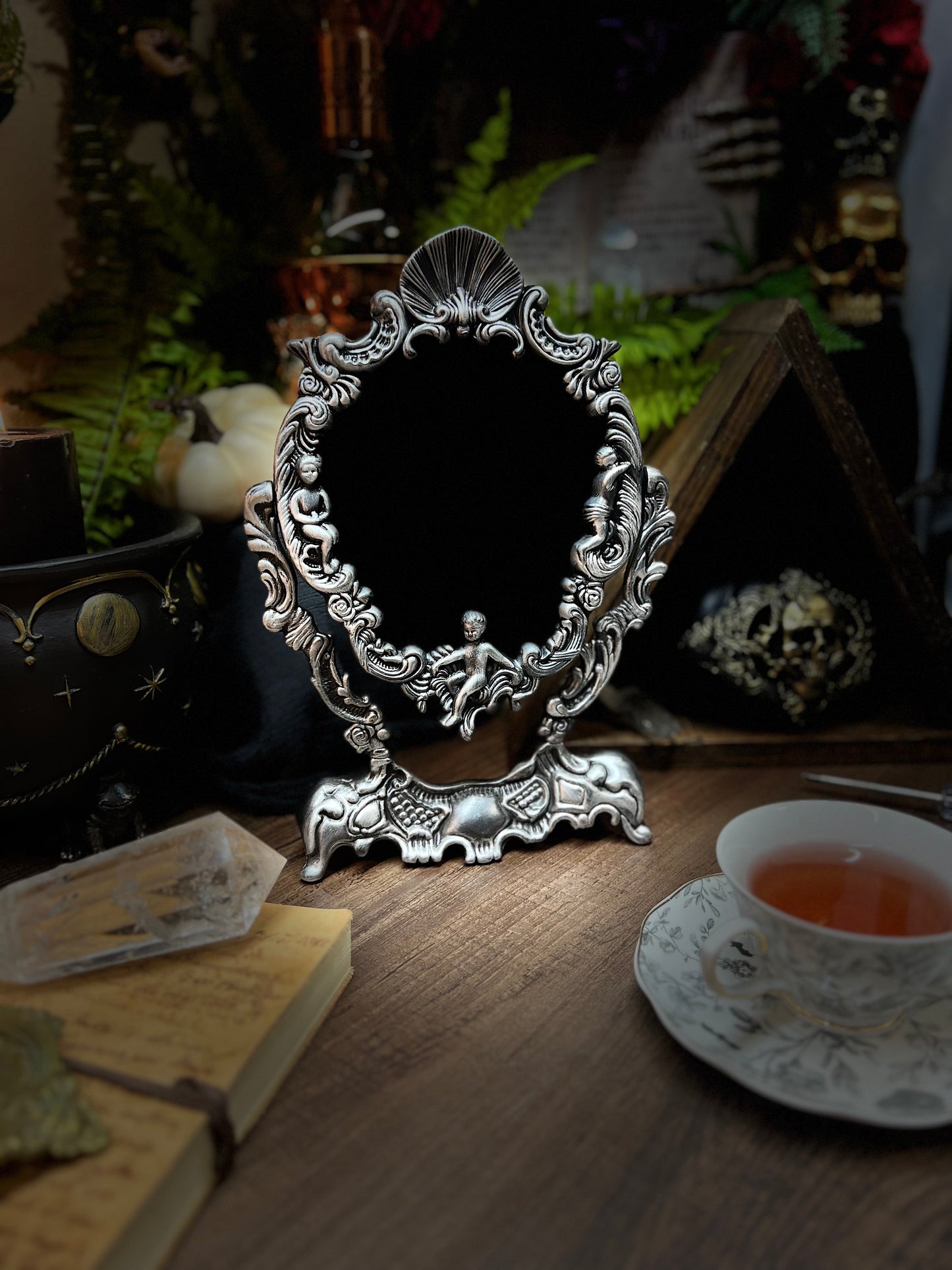 Large heirloom antique divination black scrying mirror with ornate metal footed tilt frame with cherubs and angels