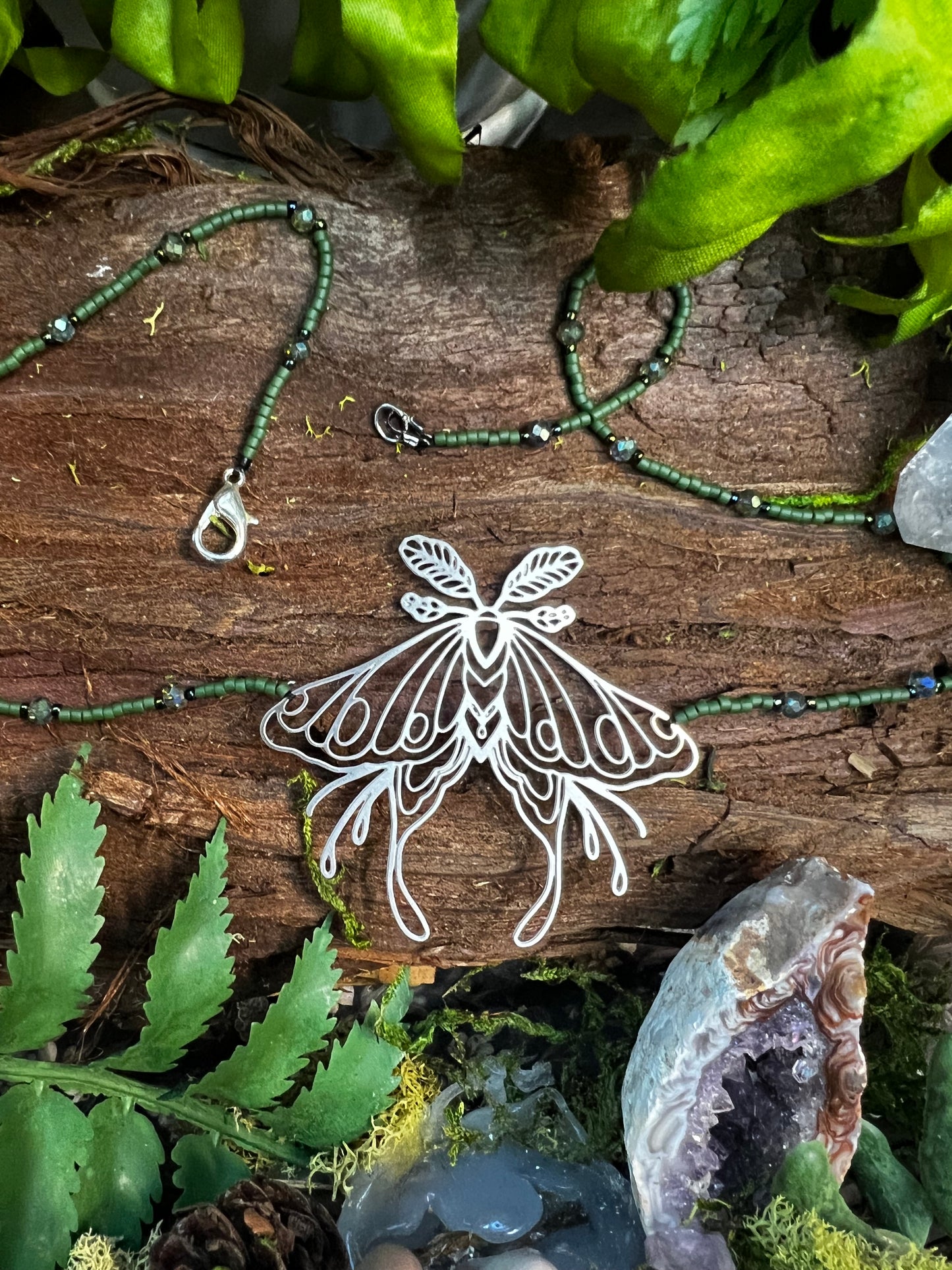 Hand-strung green beaded luna moth necklace displayed with moonlit forest aesthetic