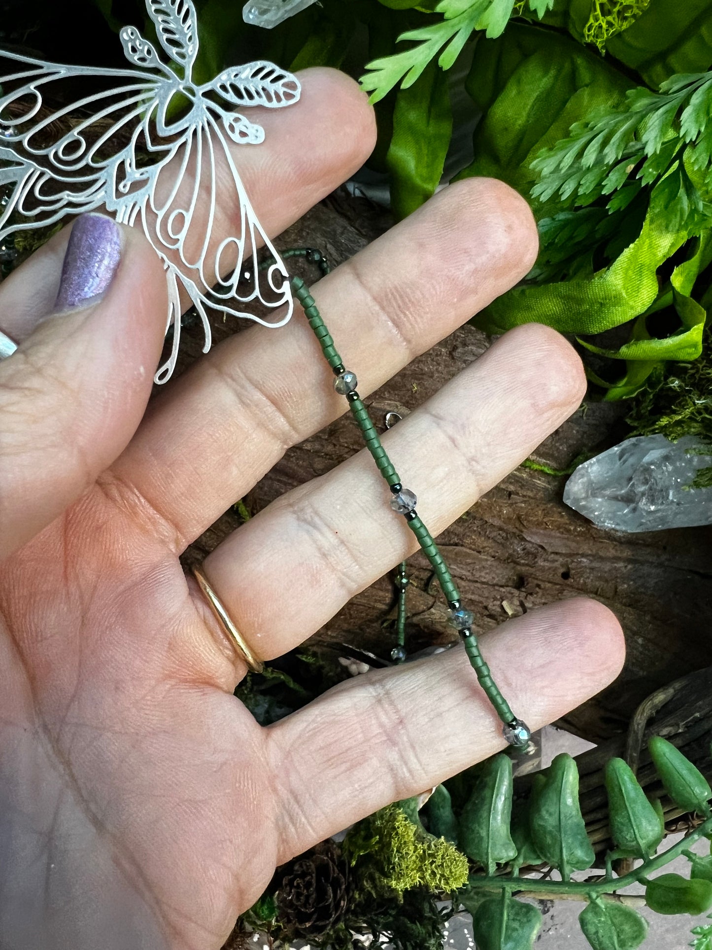 Necklace arranged in a circle on wooden surface, highlighting delicate beading and enchanting moth pendant