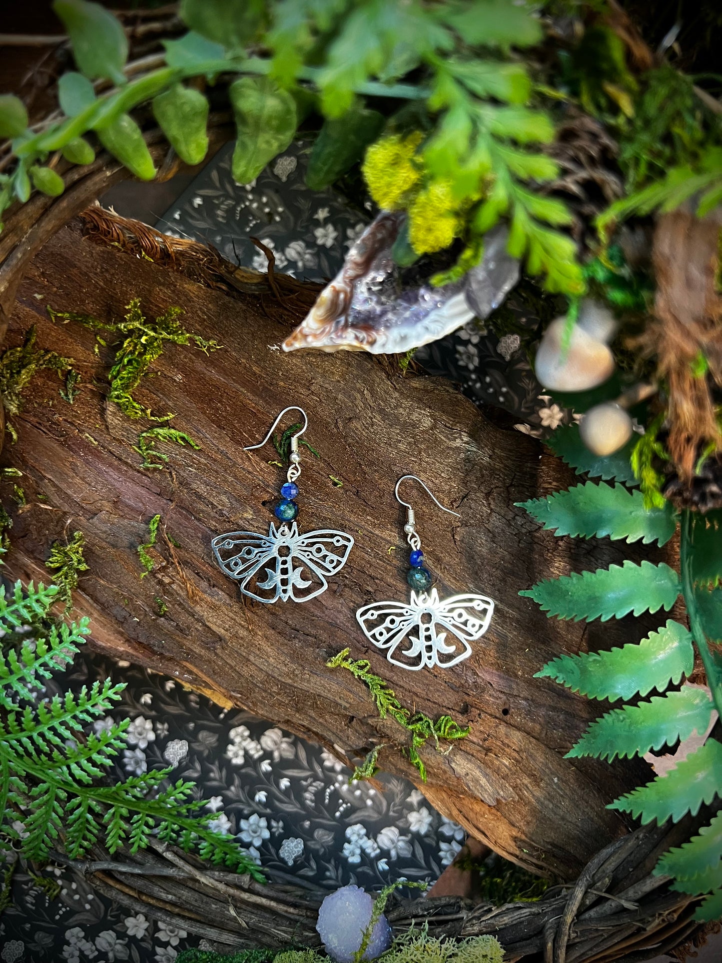 Handmade mystical earrings featuring blue gemstones and detailed moth charms.