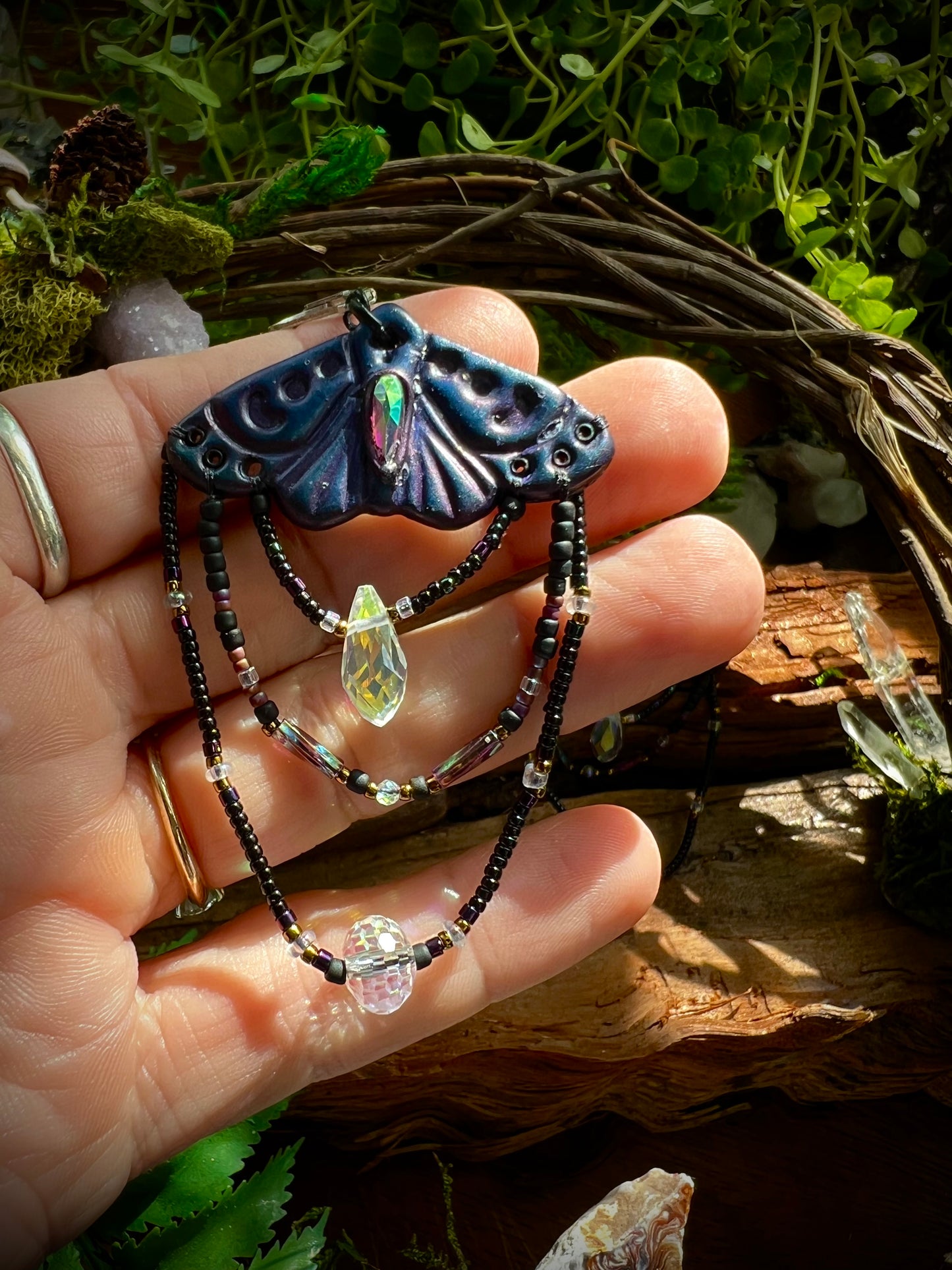Forest-fairy inspired moth earrings displayed against rustic wood and greener