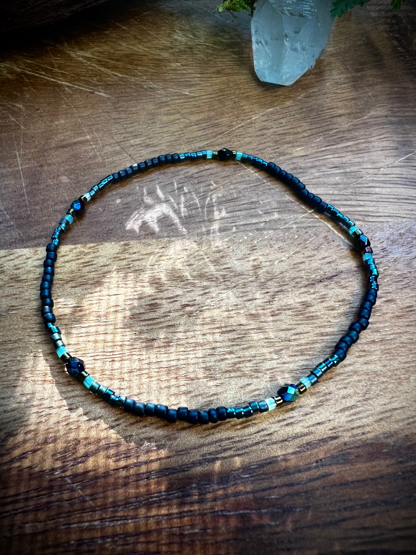 Black blue and teal seed beaded bracelet on a wooden surface