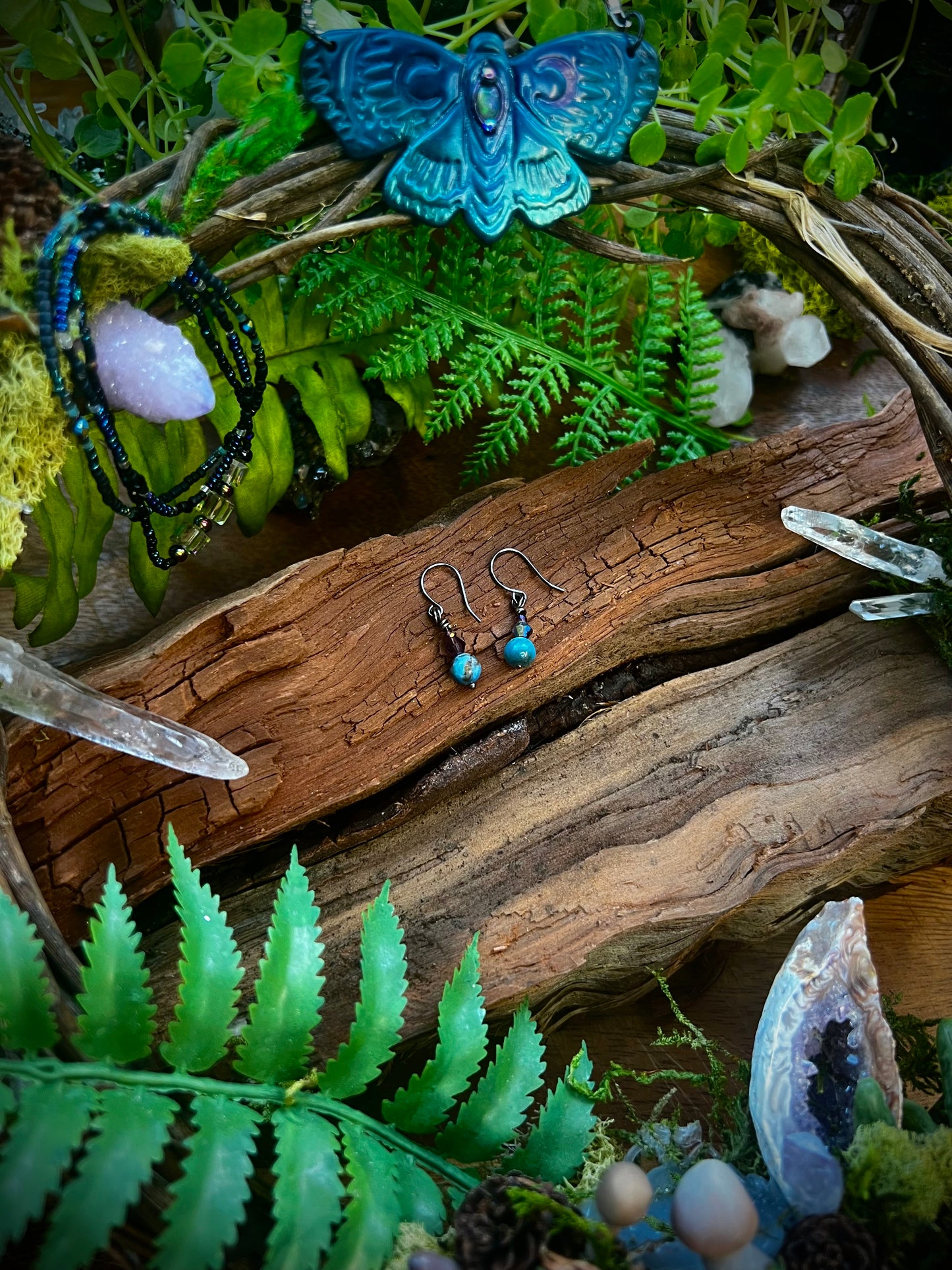 Lightweight apatite earrings styled on rustic wood with forest ferns