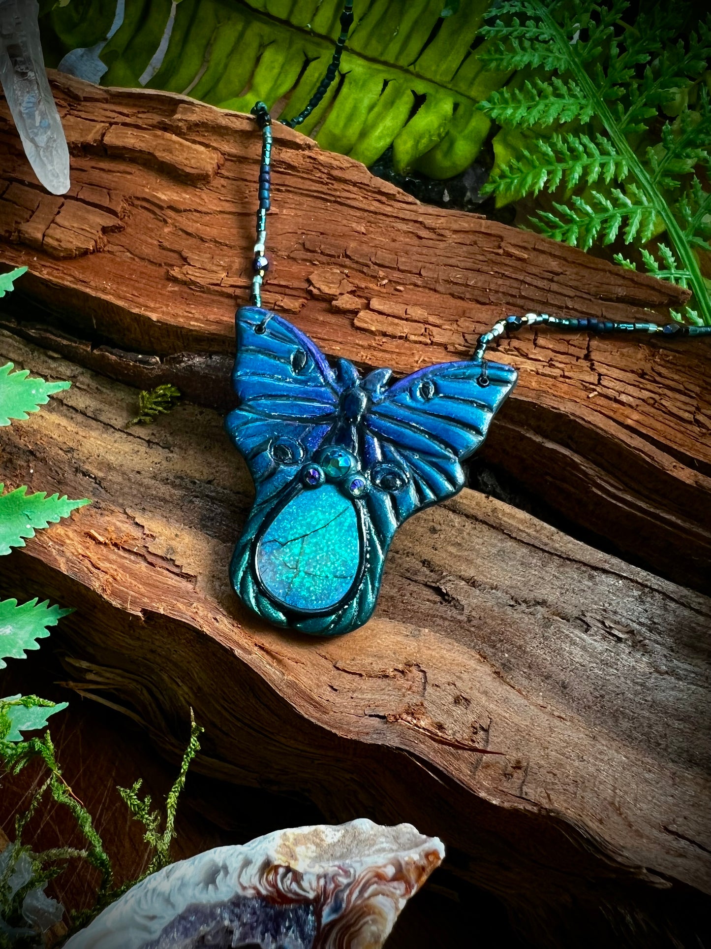 Mystical luna moth necklace styled among moss and quartz accents