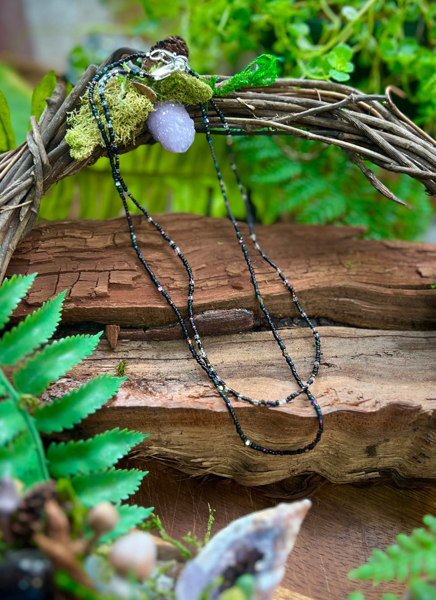 Delicate seed bead layering necklaces with aurora-inspired beads on natural wood background