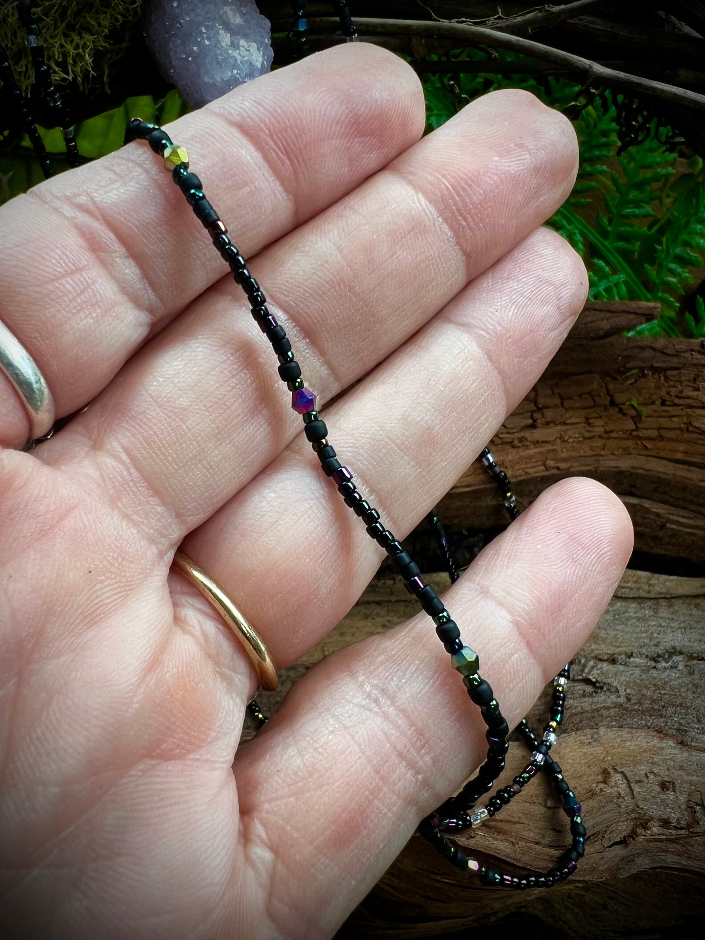 Patterned aurora seed bead necklace with shimmering iridescent beads displayed in hand
