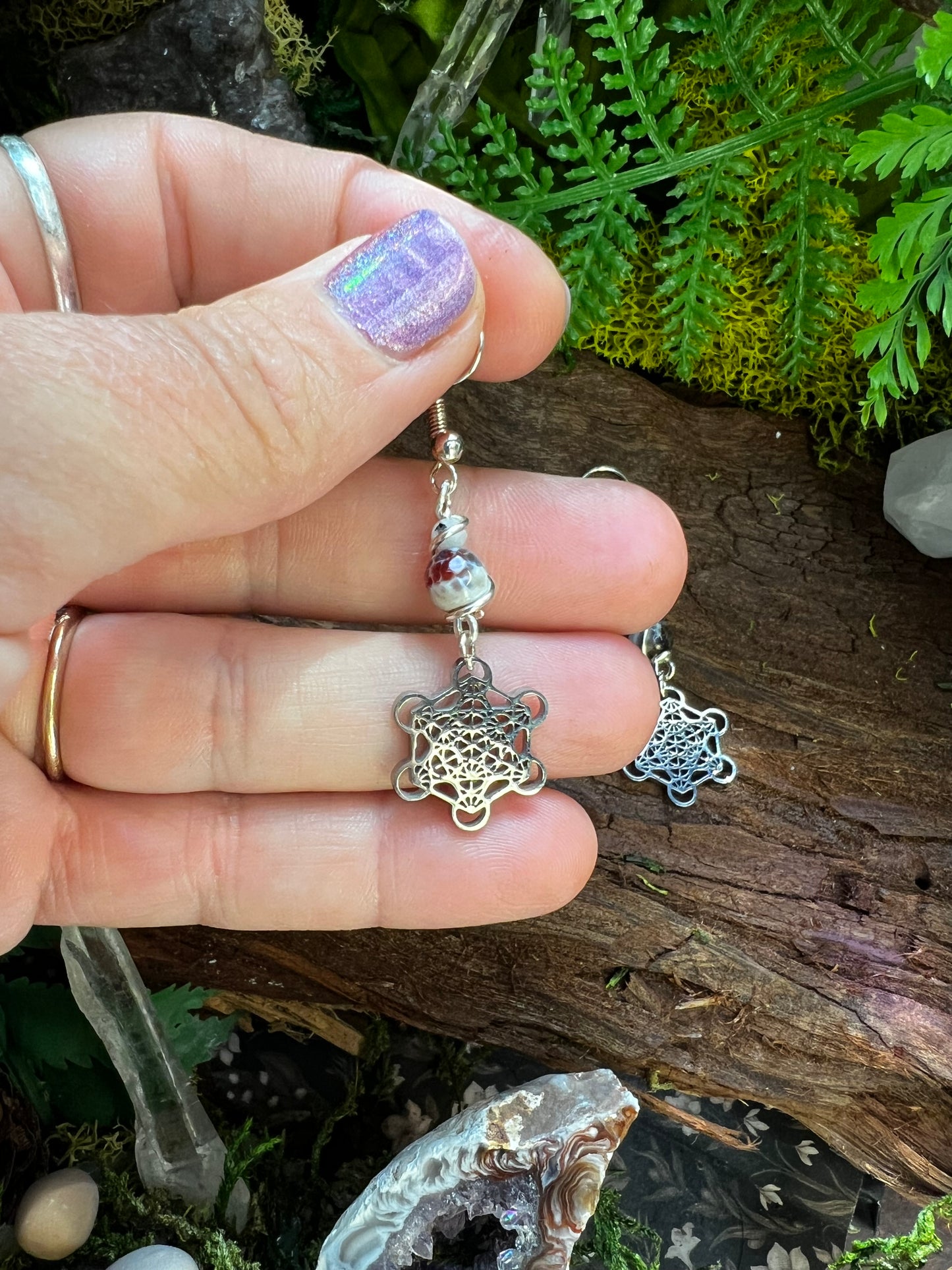 Mystical sacred geometry earrings with agate beads resting on a wooden background