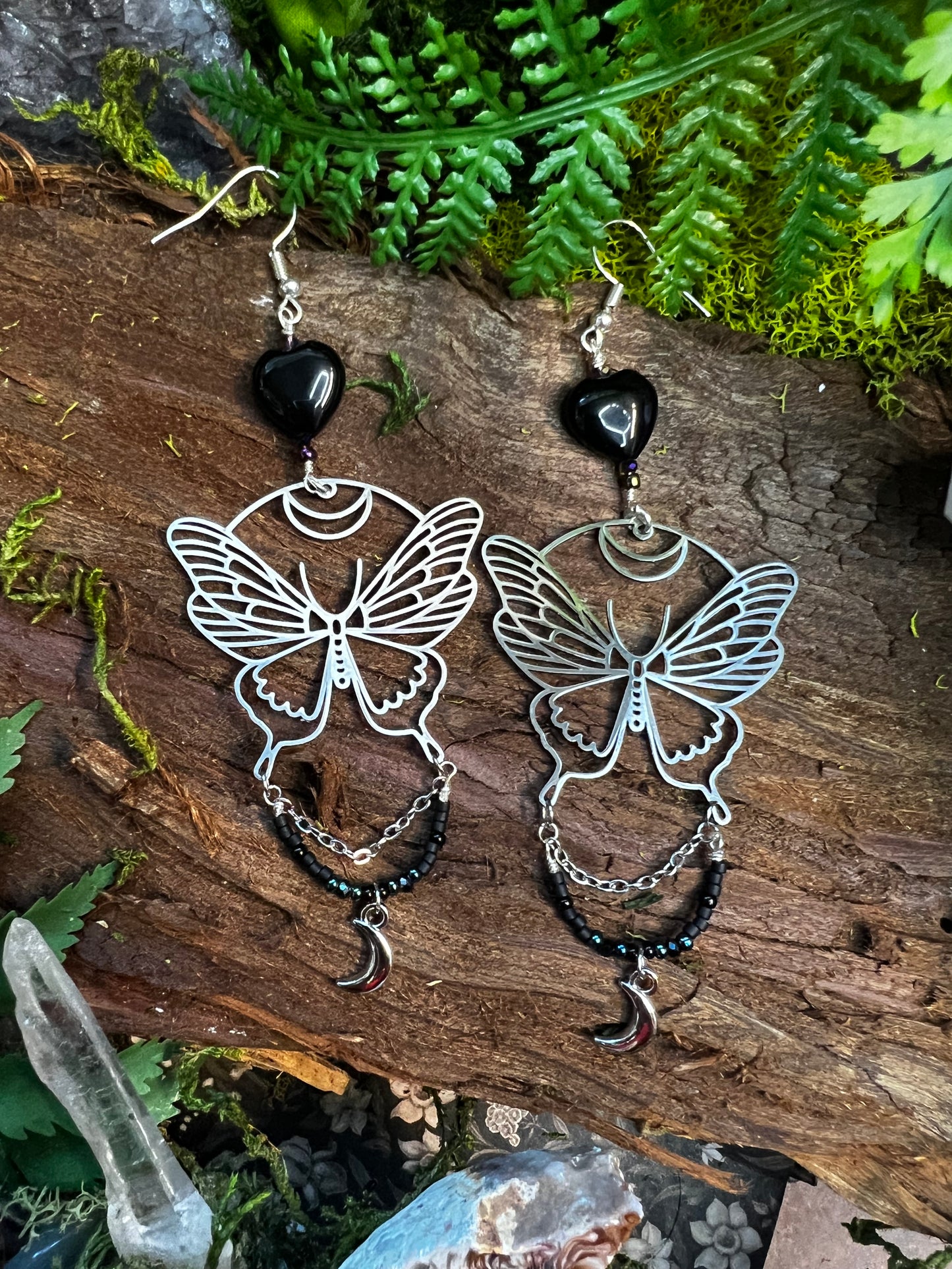Mystical moon moth earrings with shimmering black agate beads and chains styled on moss
