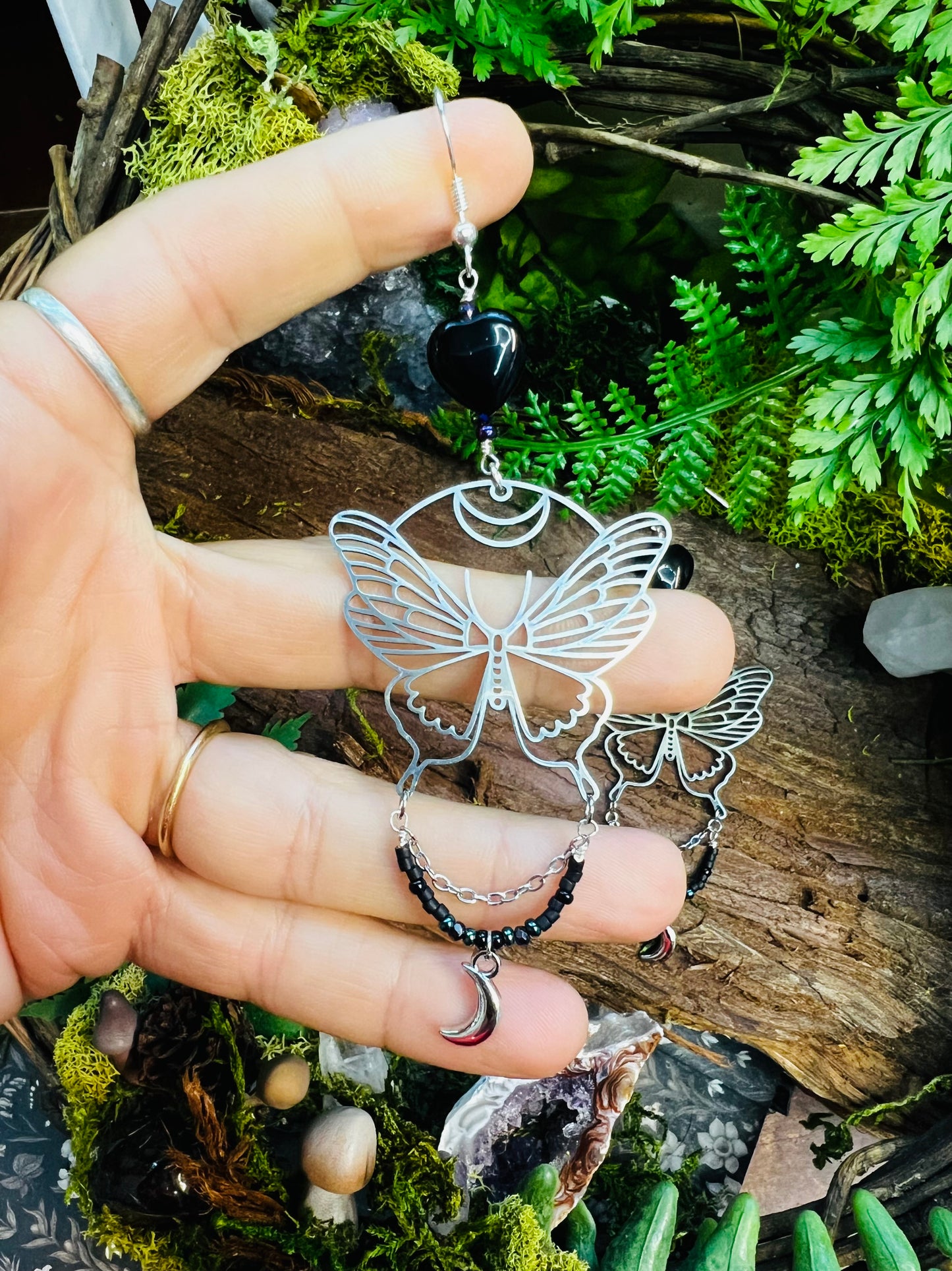 Magical transformation earrings with black agate and moon phases resting on rustic background