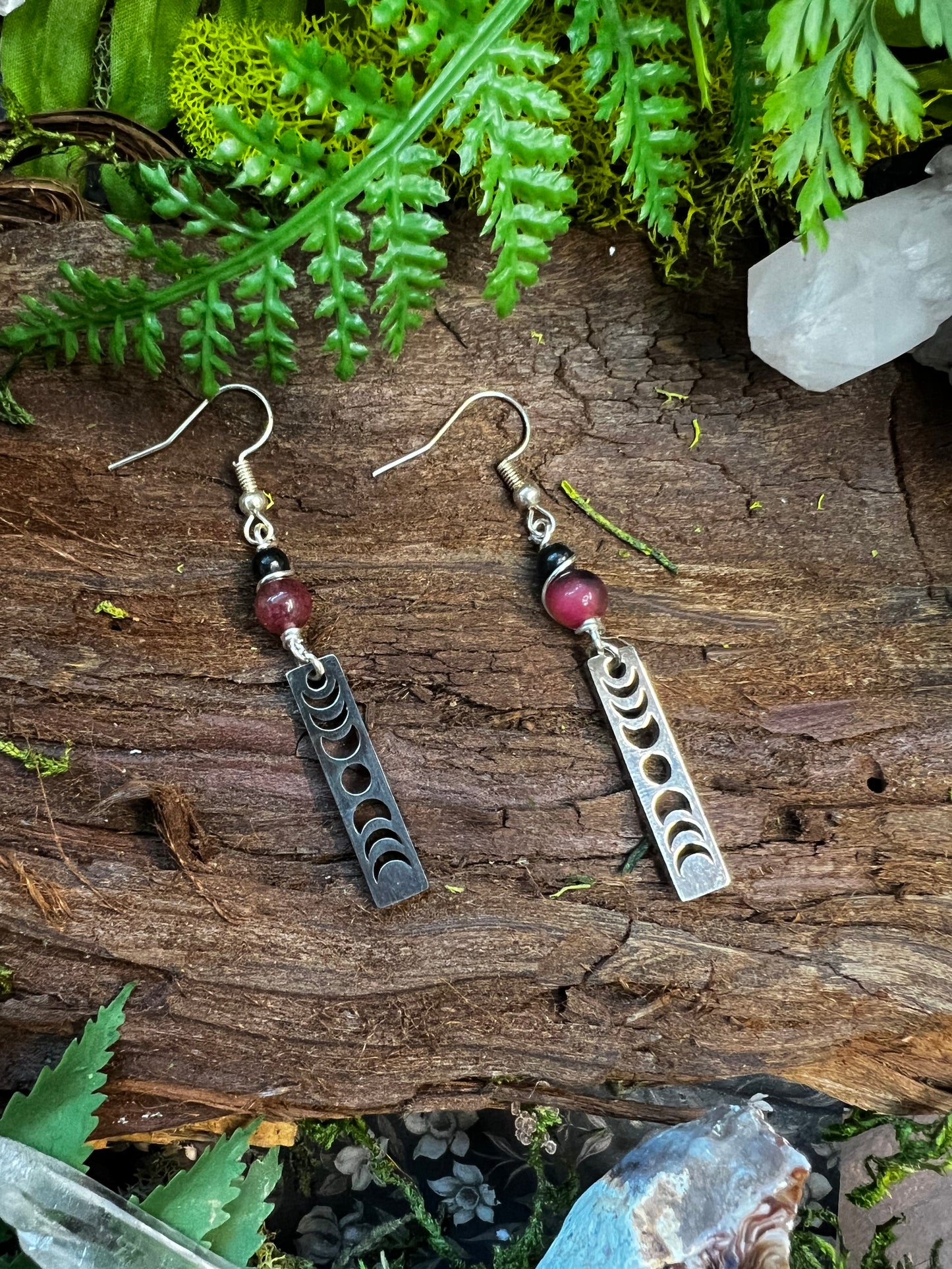 Dyed jade and obsidian lunar phase earrings styled on wood with moss and crystals