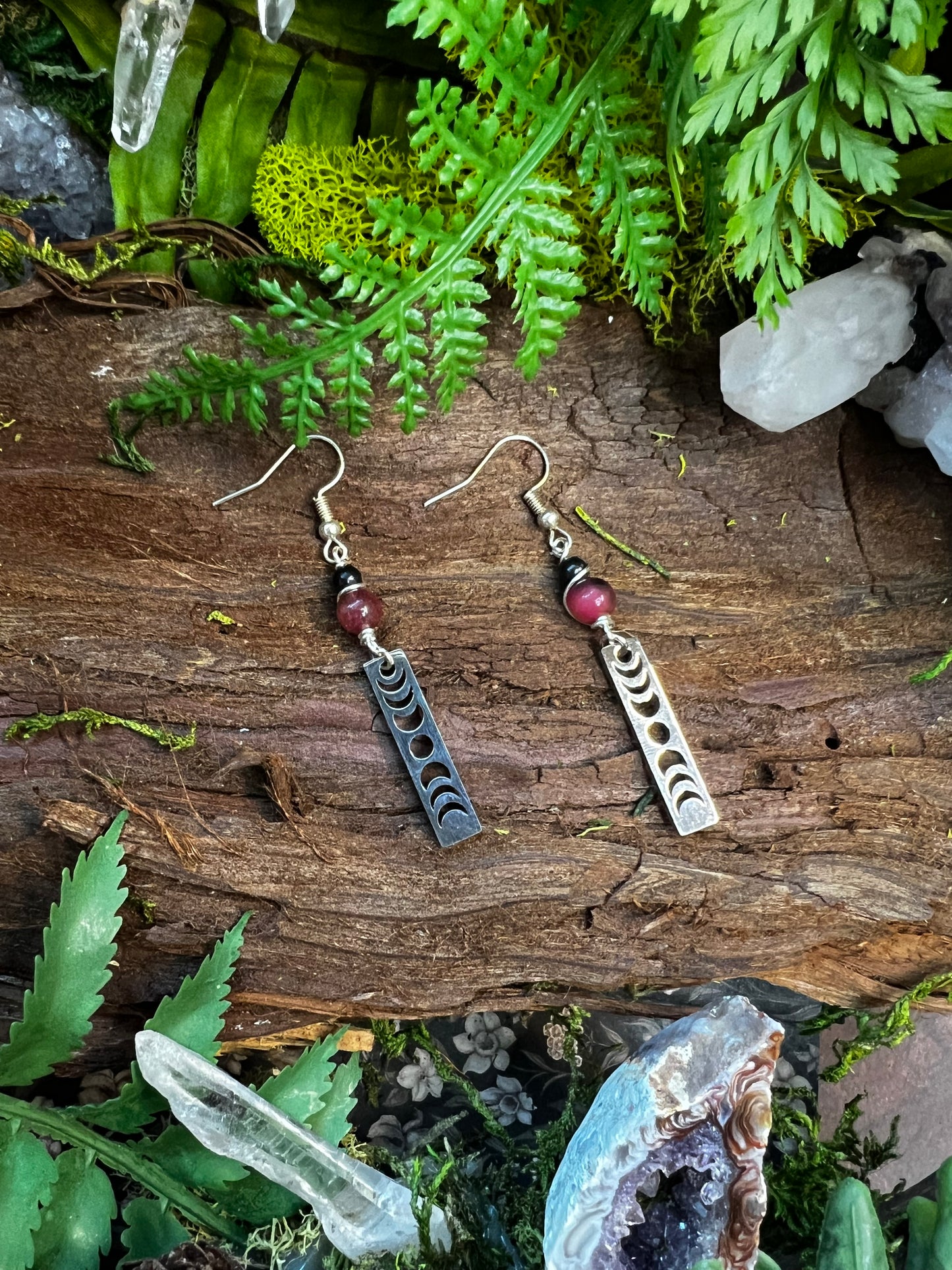 Dyed jade and obsidian lunar phase earrings styled on wood with moss and crystals