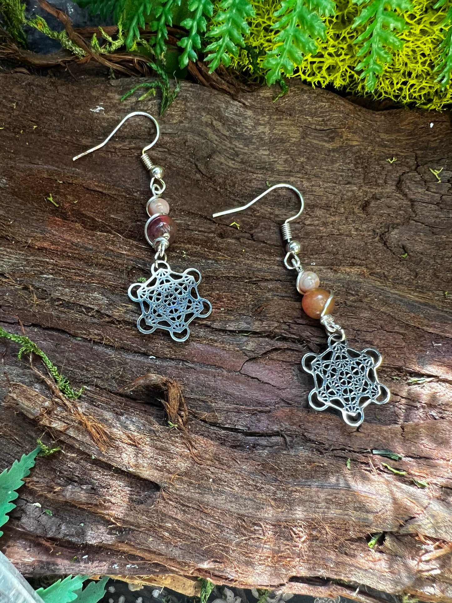 Lightweight mystical earrings featuring pink jade and Metatron’s Cube design in a forest scene
