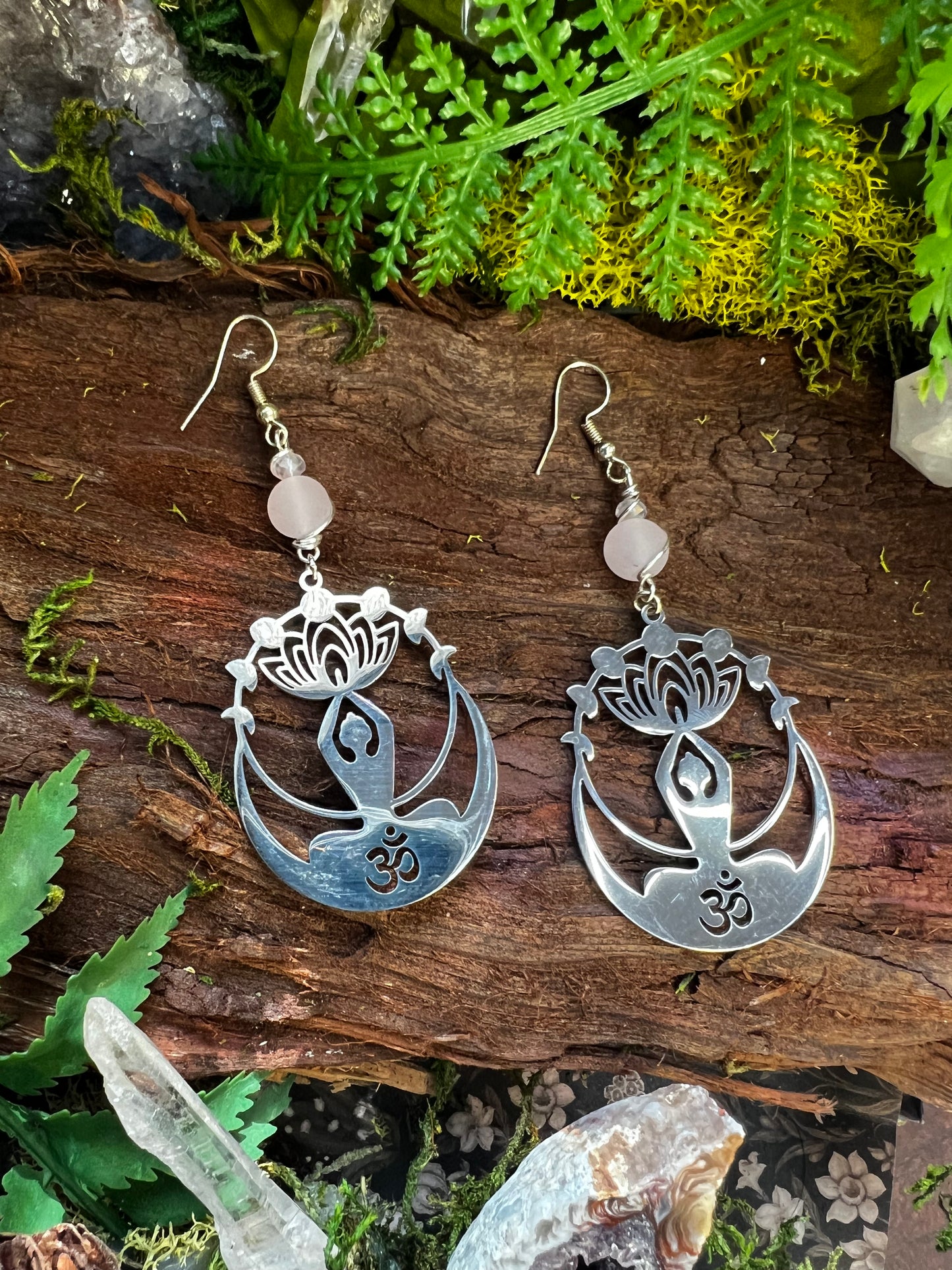 Lightweight Om and lotus earrings with healing crystal beads resting on wood