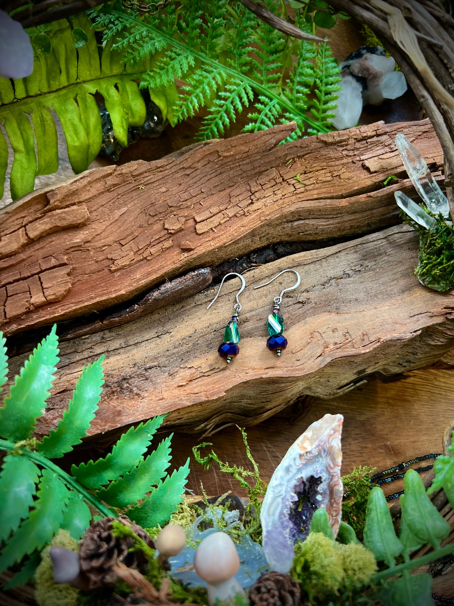 Close-up of green and blue faceted crystal earrings glowing in light