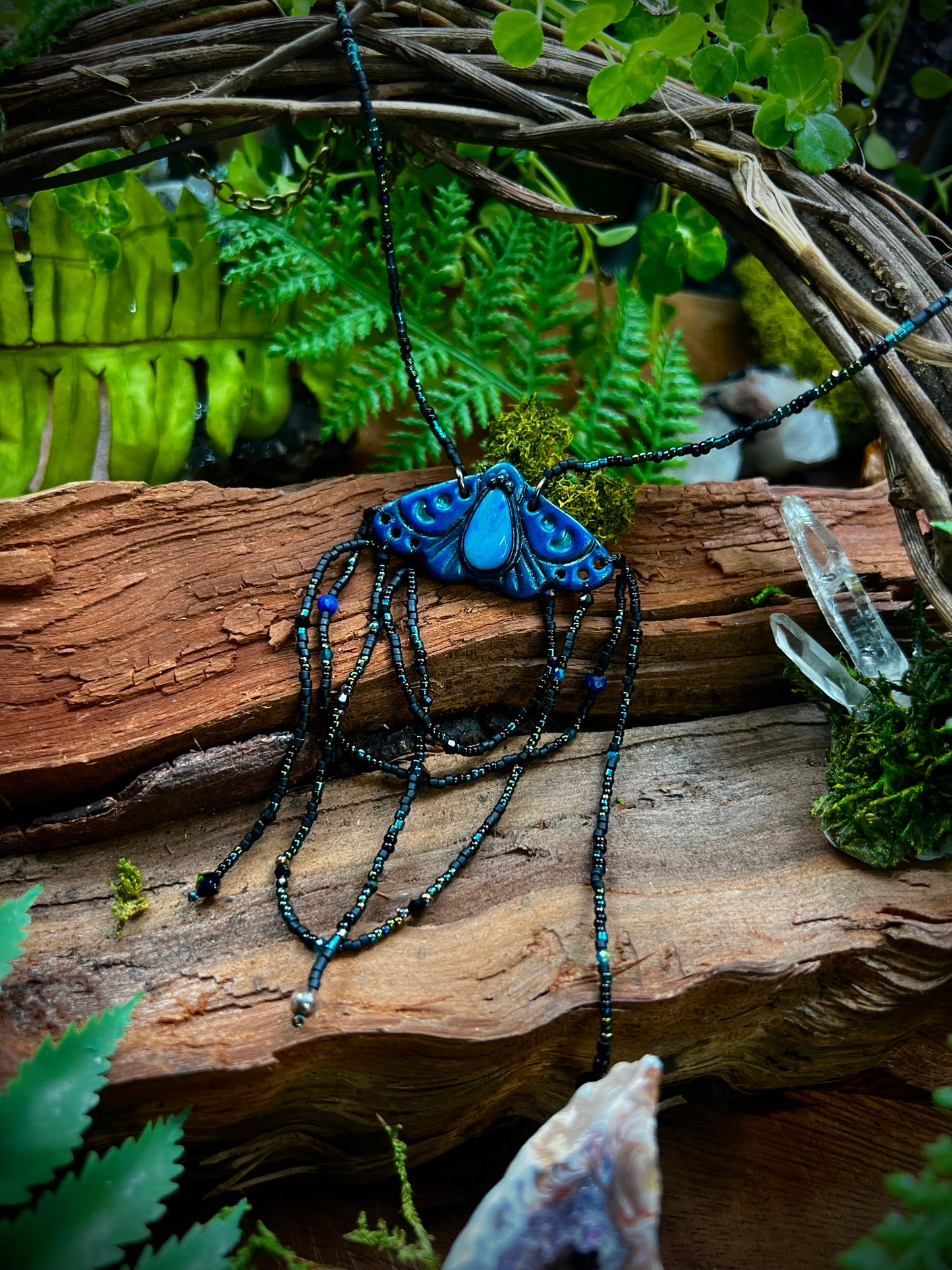 Close-up of opal centerpiece glowing in hand-sculpted moth pendant
