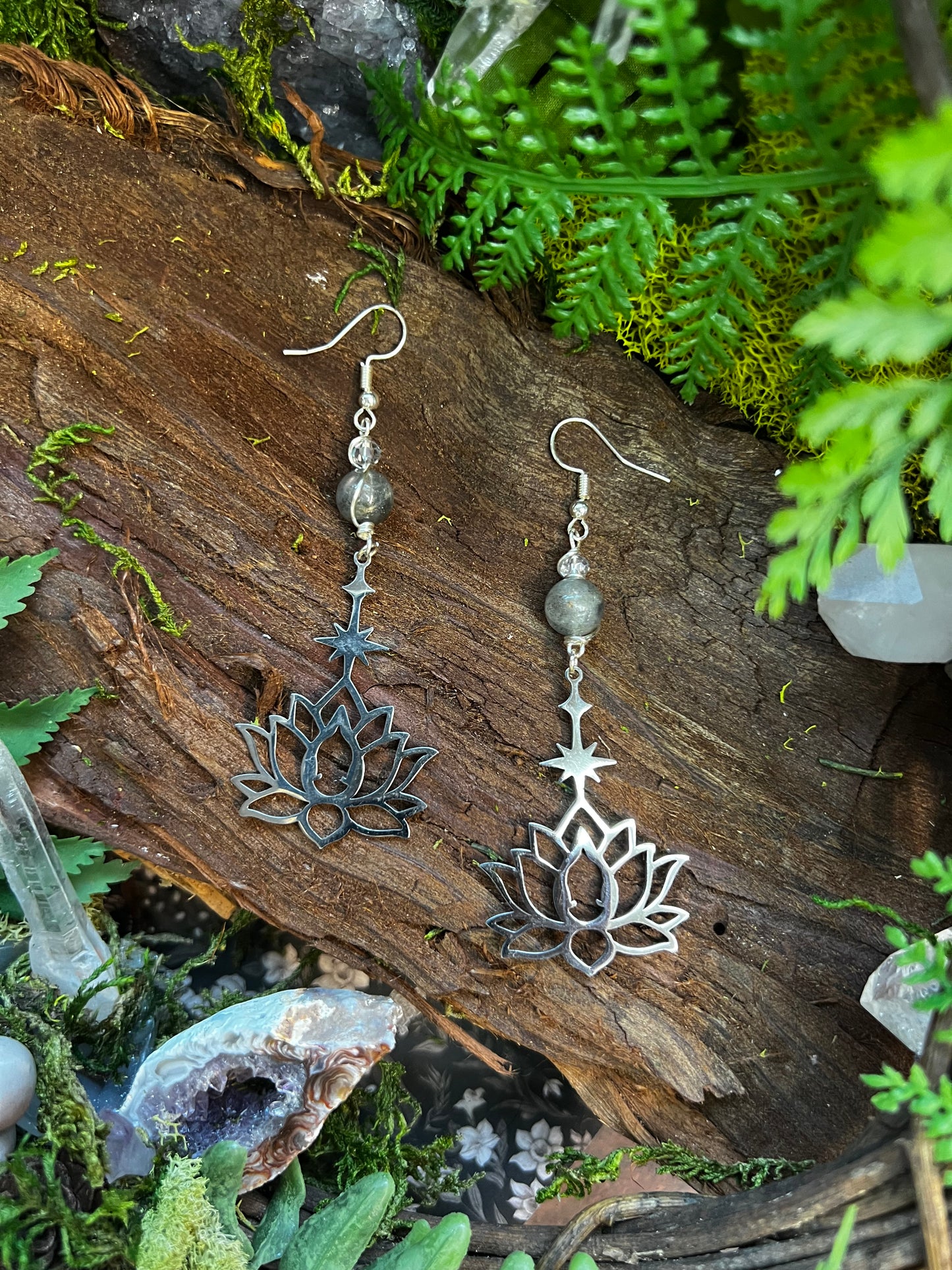Mystical crystal earrings with lotus and star design on rustic natural background