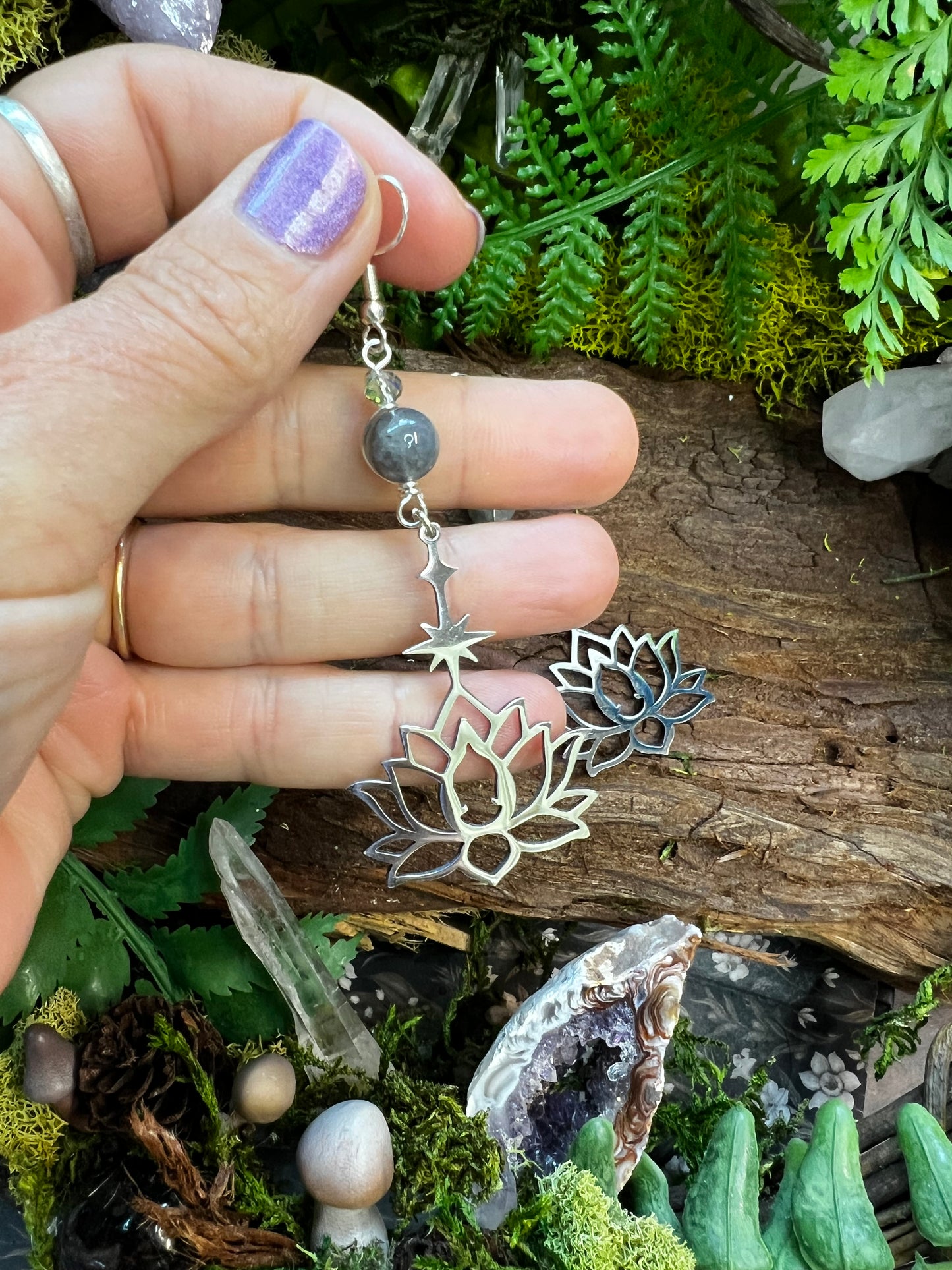 Labradorite and clear quartz earrings surrounded by greenery and crystal accents
