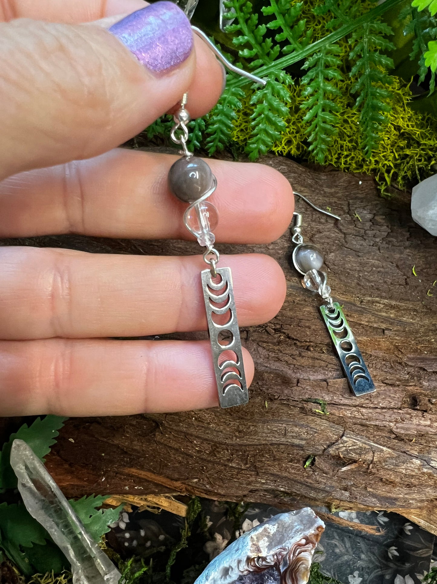 Grounding petrified wood and clear quartz earrings surrounded by greenery