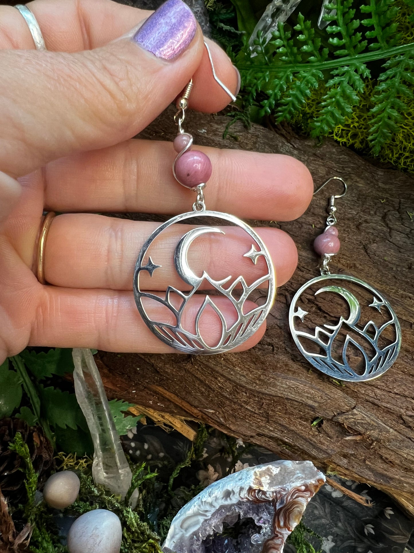 Lightweight rhodonite earrings with spiritual moon and lotus design on rustic background