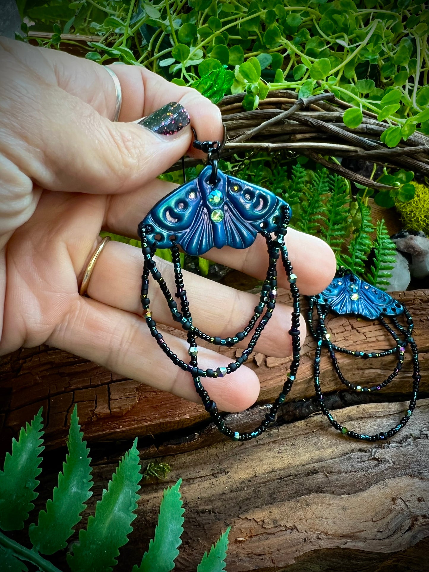 Close-up of crystal accents on woodland moth earrings glowing in light