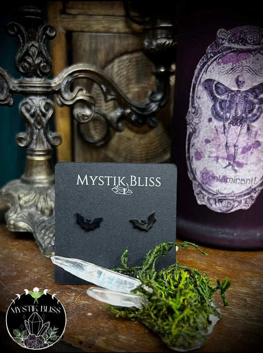 Mystik Bliss bat earrings on a dark card with decorative background