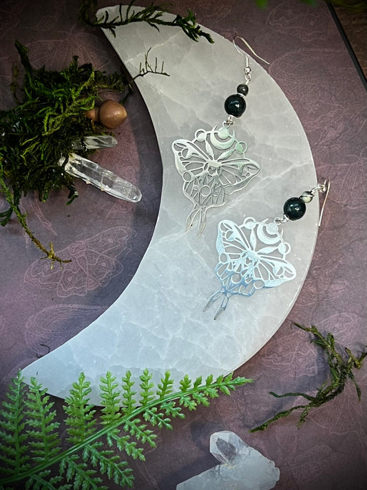 Ocean jasper moth and moon earrings resting on a moon phase background with forest accents