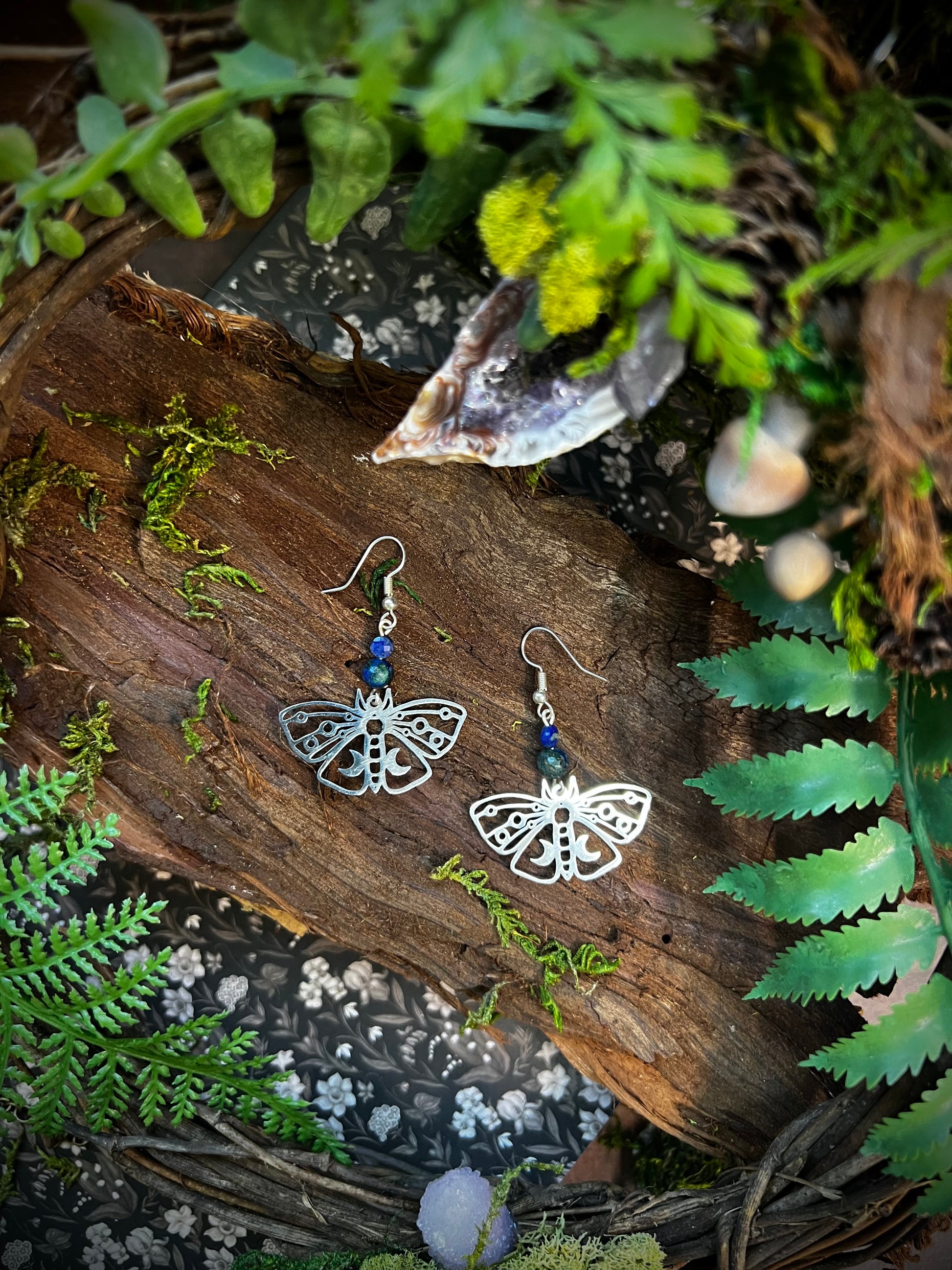 Handmade mystical earrings featuring blue gemstones and detailed moth charms.