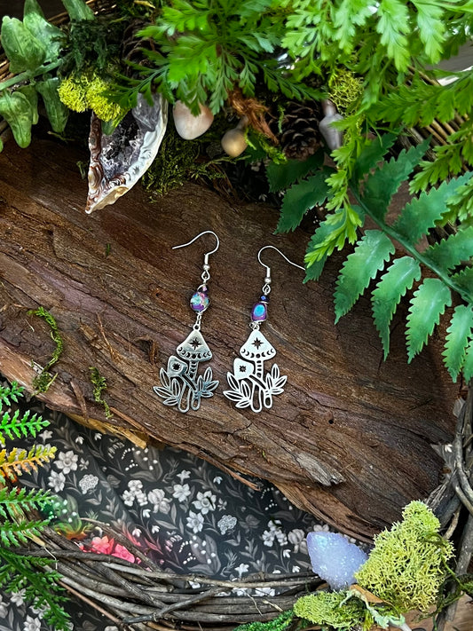 Sea sediment jasper mushroom earrings resting on a wood and moss forest backdrop