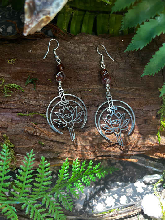Fire Quartz and stainless steel lotus sword earrings on rustic wood background