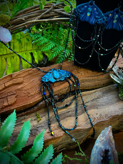 Hand-sculpted polymer clay moth pendant with twilight blue finish and crystal accents