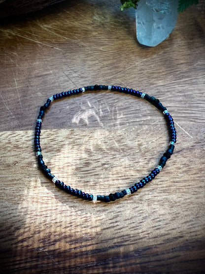 Necklace with blue and black beads on a wooden surface