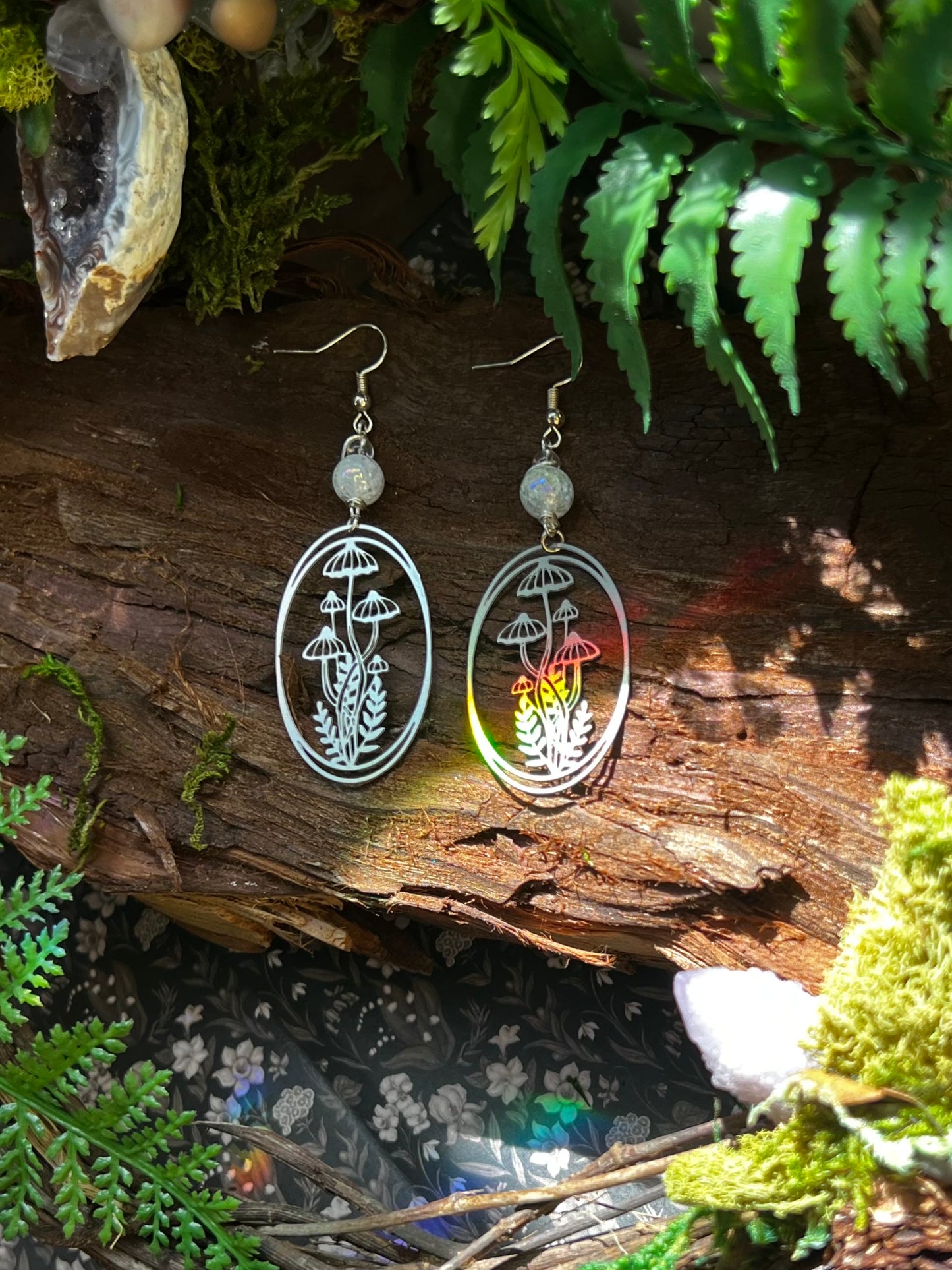Oval-shaped mushroom earrings with aura crackle quartz beads on a rustic wood background
