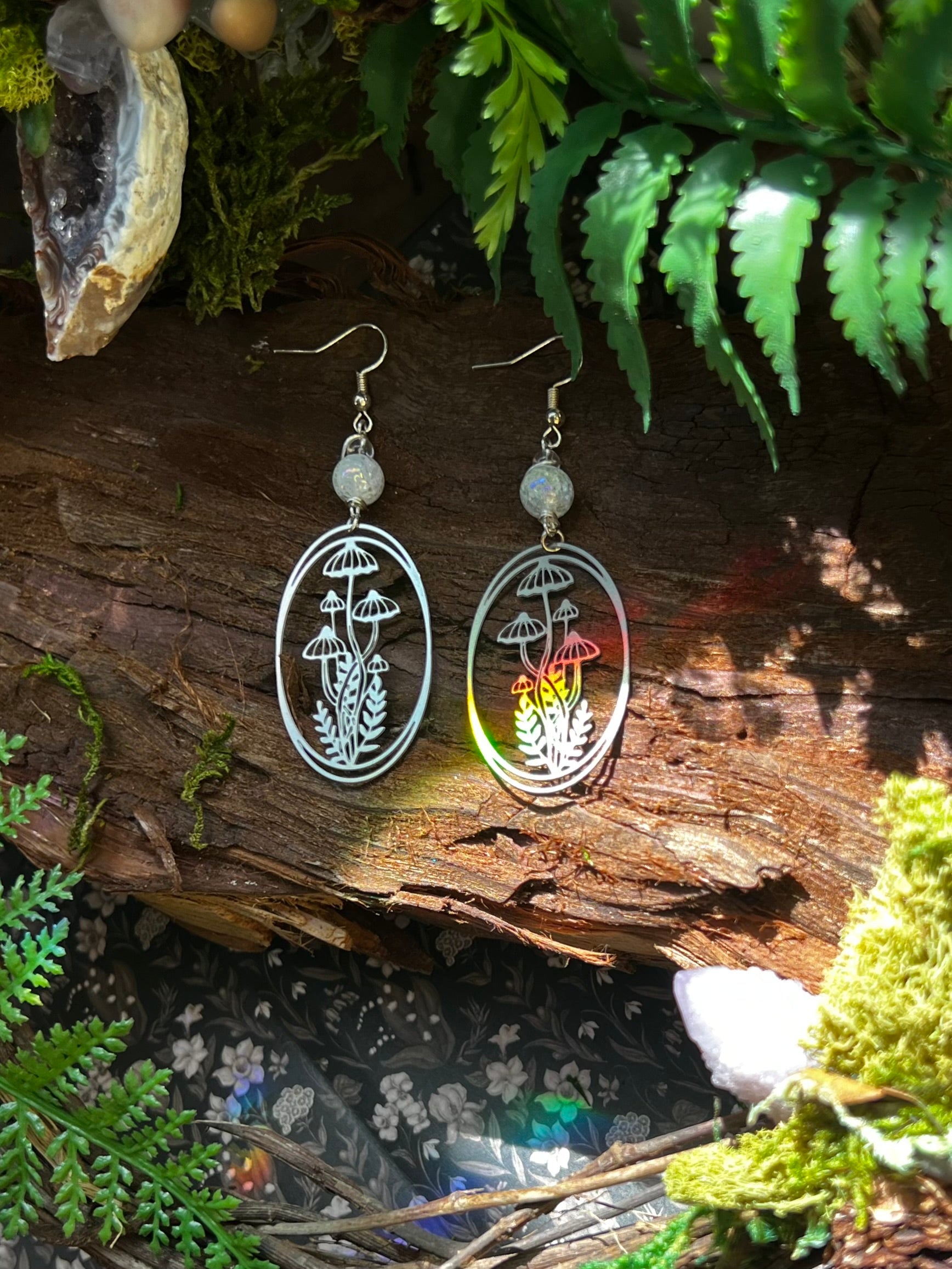 Oval-shaped mushroom earrings with aura crackle quartz beads on a rustic wood background