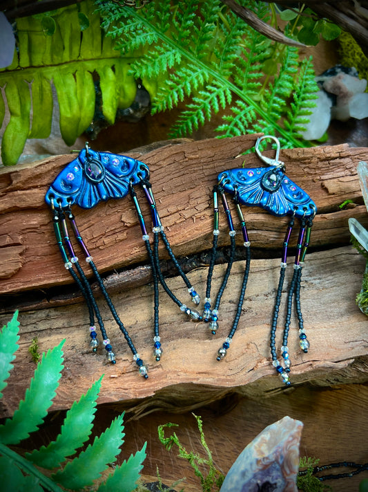 Woodland moth earrings with polymer clay wings and crystal center displayed on wood