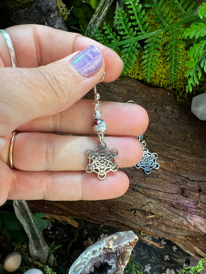 Mystical sacred geometry earrings with agate beads resting on a wooden background