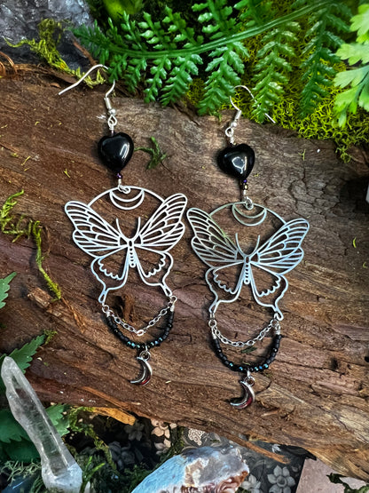 Mystical moon moth earrings with shimmering black agate beads and chains styled on moss