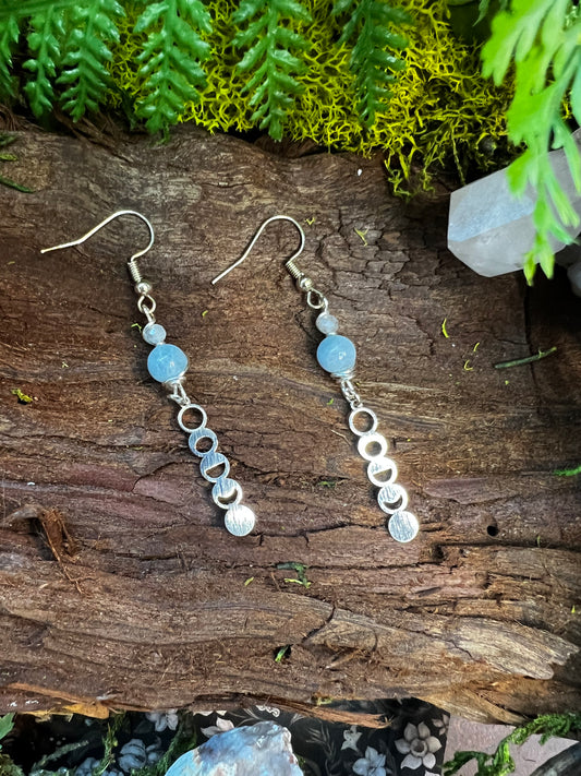 Aquamarine and faceted moonstone lunar earrings styled on moss and wood