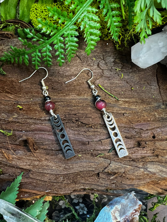 Dyed jade and obsidian lunar phase earrings styled on wood with moss and crystals