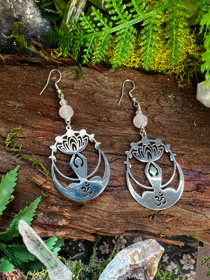 Lightweight Om and lotus earrings with healing crystal beads resting on wood