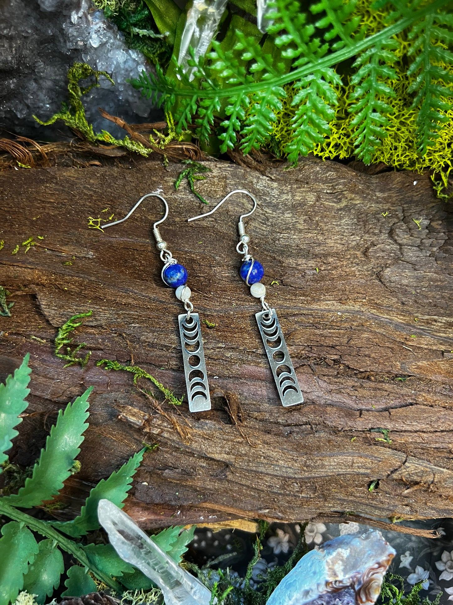 Deep blue and soft moonstone earrings with moon phase charms on a natural backdrop