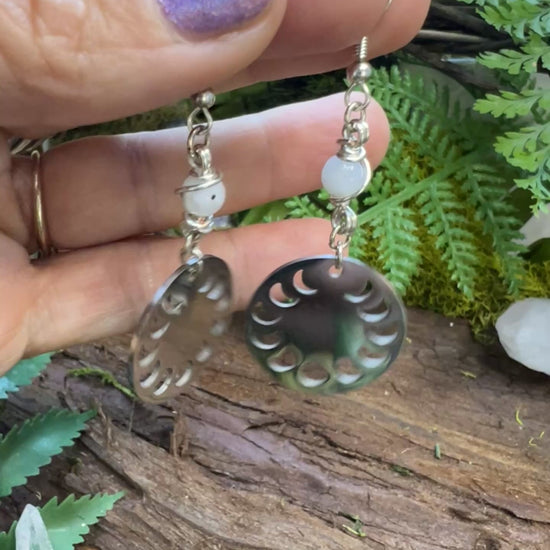 Emotional balance earrings with moon charms and rainbow moonstone on wood