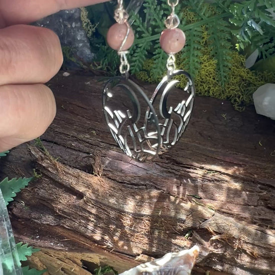 Pink crystal and moon earrings styled with greenery and wood, symbolizing self-expression