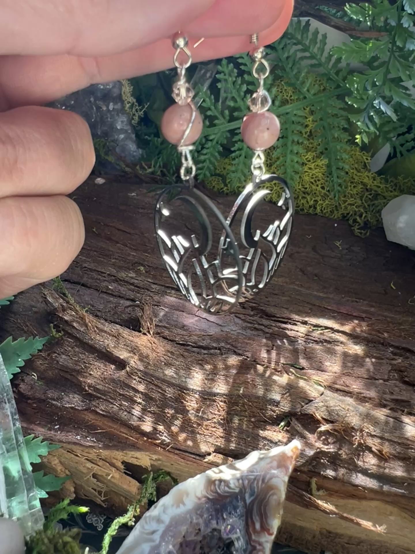 Pink crystal and moon earrings styled with greenery and wood, symbolizing self-expression