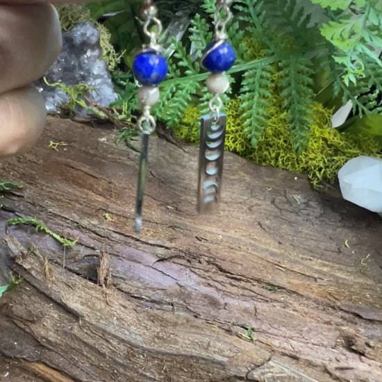 Lunar cycle earrings with healing crystals resting on forest textures