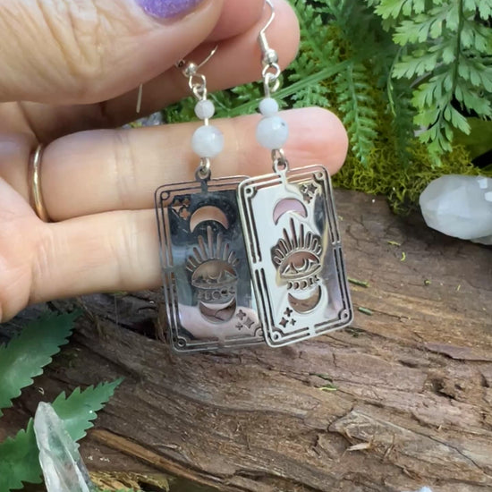 Intuitive jewelry with rainbow moonstone and tarot card symbols on wooden surface

