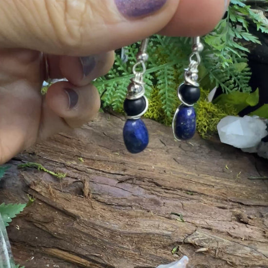 Protective lapis and onyx earrings surrounded by greenery and natural textures