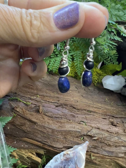 Protective lapis and onyx earrings surrounded by greenery and natural textures