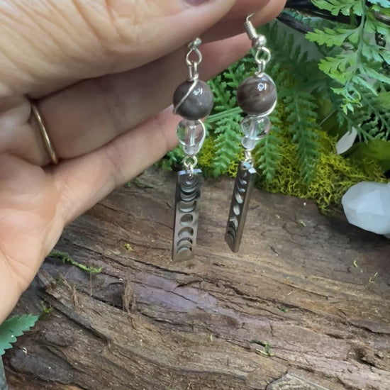 Lunar phase crystal earrings with petrified wood and quartz beads on rustic wood