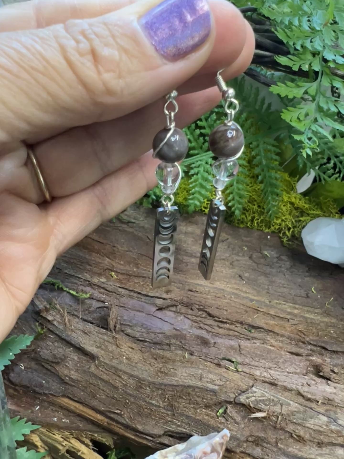 Lunar phase crystal earrings with petrified wood and quartz beads on rustic wood