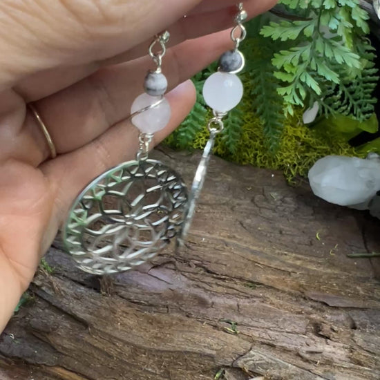 Emotional healing crystal earrings with pink beads and moon phases surrounded by moss